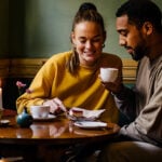 Man and woman drink a cup of coffee together and laugh and she thinks about how to ask for a second date